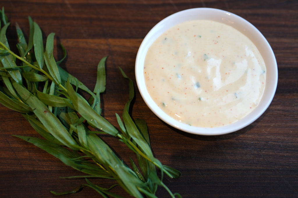 Malt aioli in small dish next to tarragon and on wood board