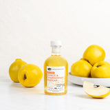 Bottle of quince and chardonnay vinegar with quince fruits on a white background