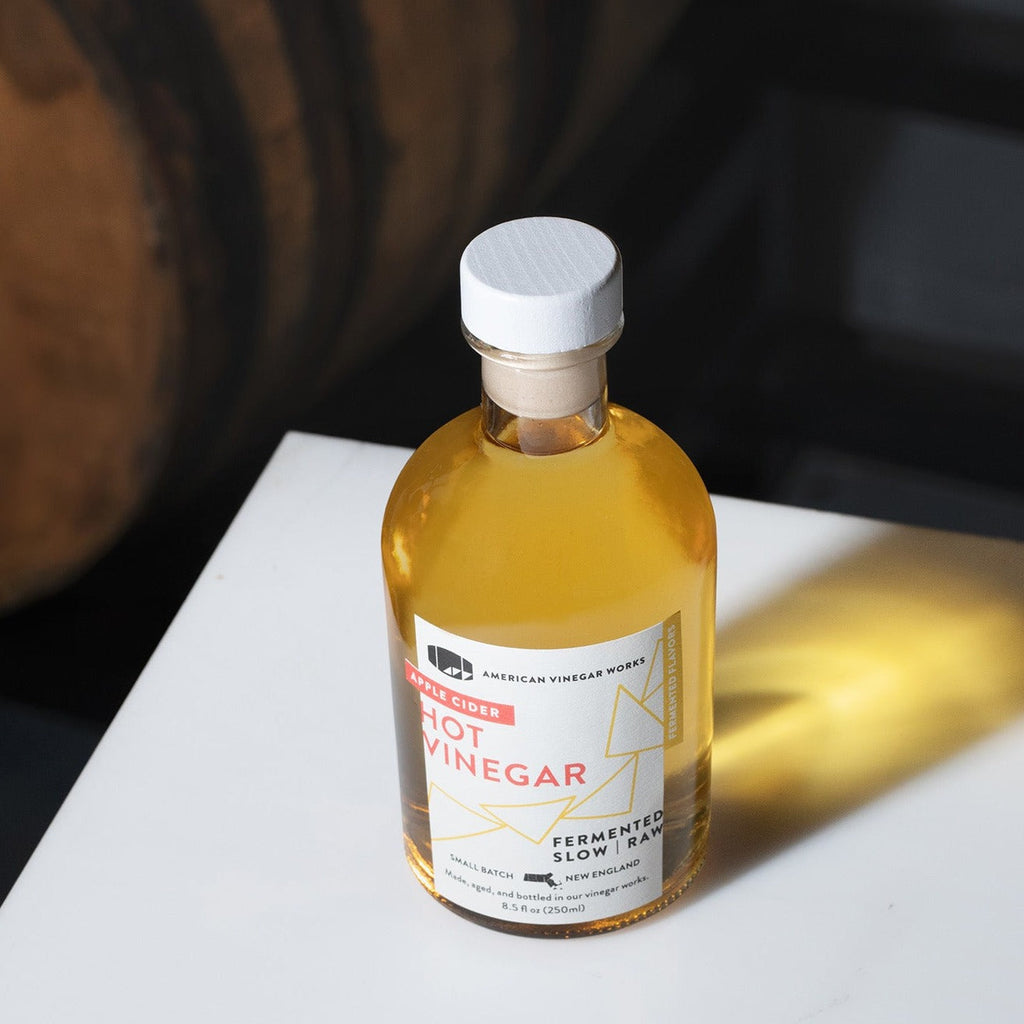 Three-quarter view of American Vinegar Works Hot Apple Cider Vinegar bottle on a white surface.