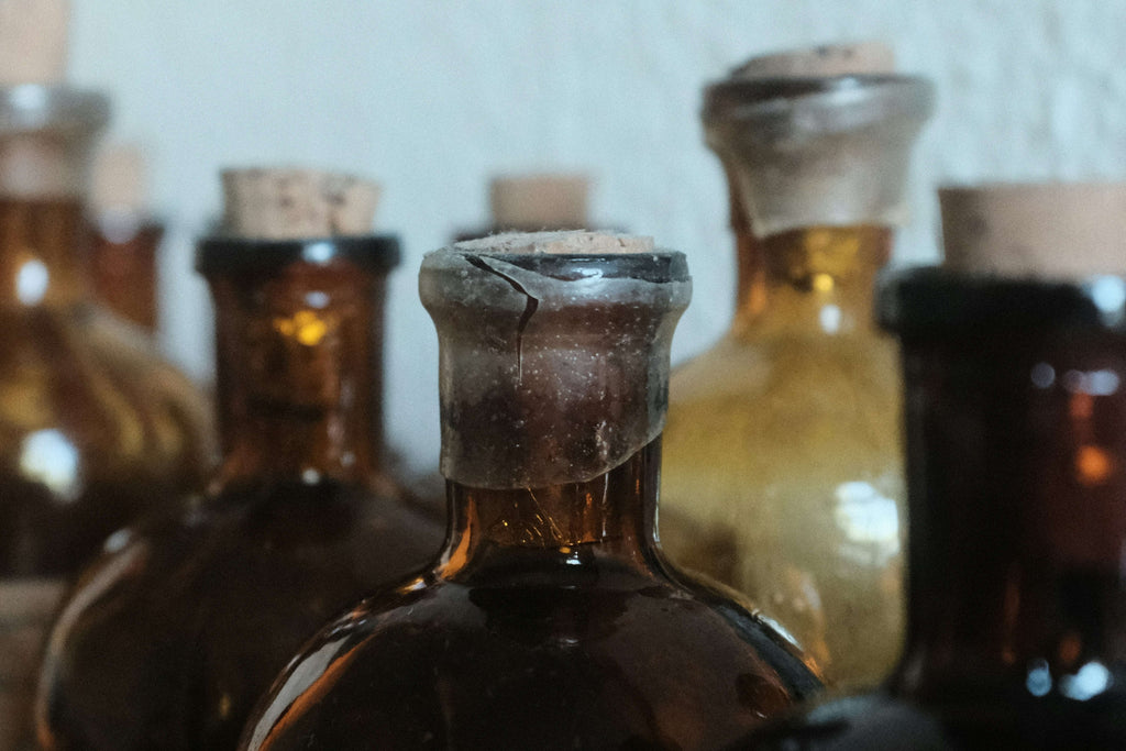 Close-up of vintage amber glass bottles with corks, one bottle shows a cracked wax seal on its neck