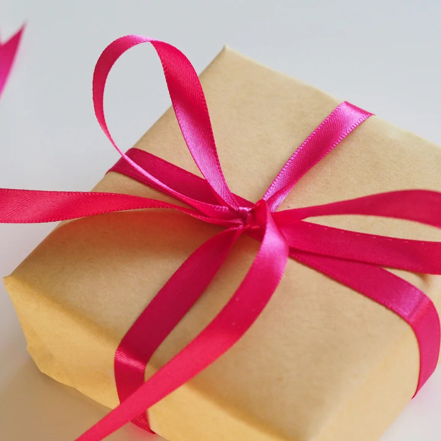 Kraft-wrapped rectangular gift box tied with bright pink satin ribbon and bow