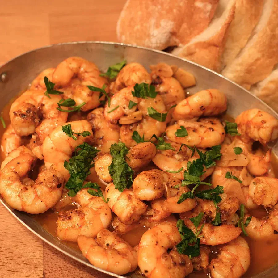 Skillet of garlic shrimp in sherry vinegar sauce, with chopped parsley and crusty background bread.