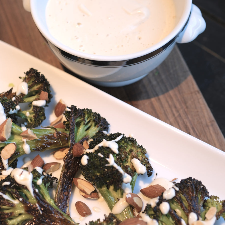 Roasted broccoli with Garlic Cashew Cream Sauce on a white serving plate