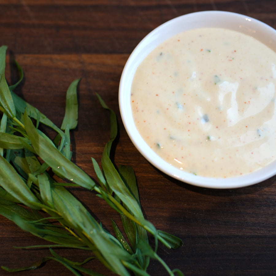 Malt aioli in small dish next to tarragon and on wood board