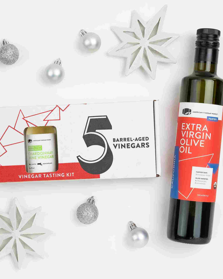 Top-down view of extra virgin olive oil and five mini vinegars in a cardboard gift box.