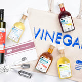 American Vinegar Works bundle: tote, olive oil, 4 vinegars, tea towel, and measuring spoons.