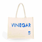 Natural canvas tote bag with "VINEGAR" in large blue letters and a logo in the bottom corner.