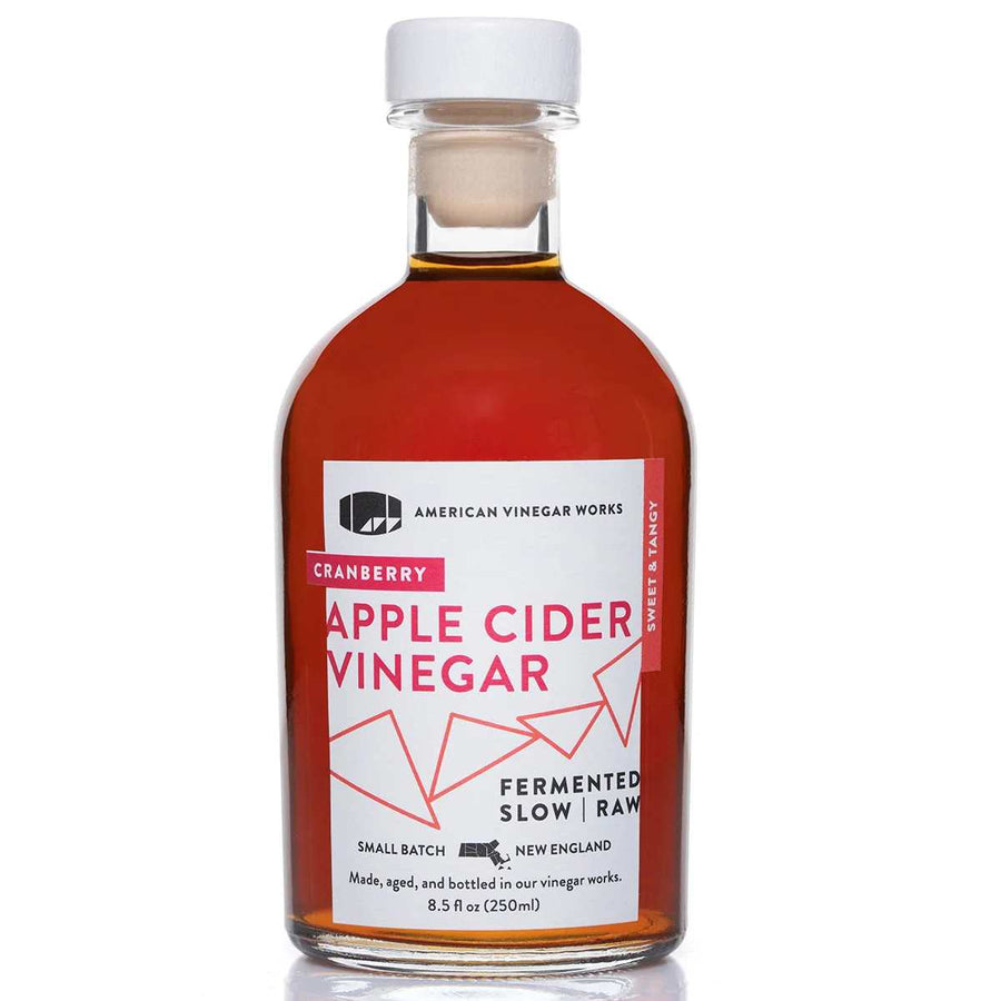 A bottle of American Vinegar Works Cranberry Apple Cider Vinegar, featuring a white cap and a rich, deep-toned liquid.