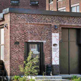 Exterior view of brick American Vinegar Works facility with an entrance sign & stacked wooden barrel