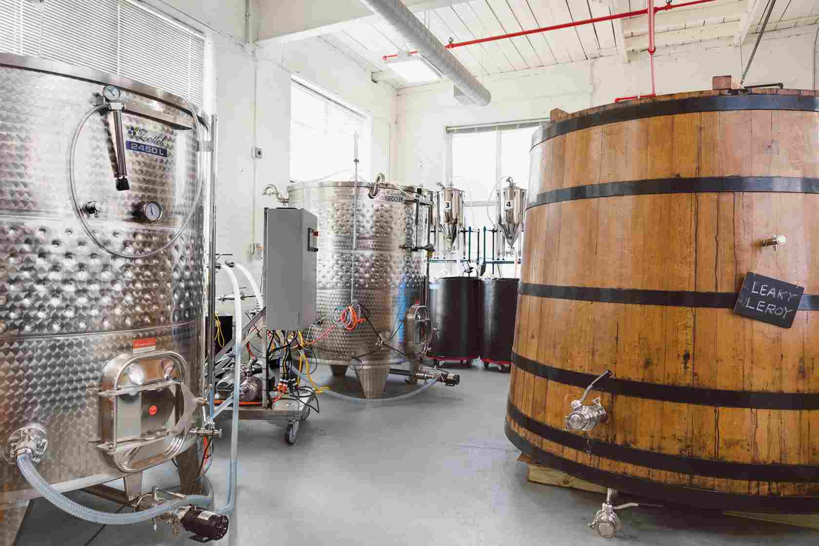 Inside the facility with stainless steel tanks and a wooden aging barrel named 