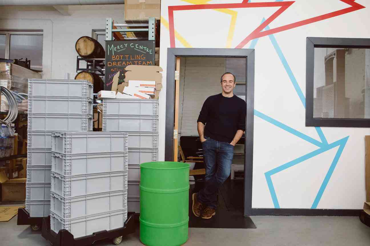 Founder Rodrigo at American Vinegar Works facility doorway, next to gray crates and a green barrel.