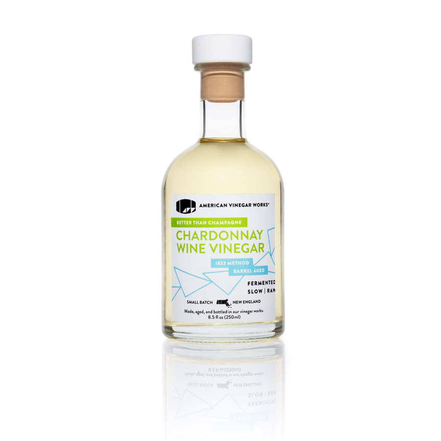 Front view of American Vinegar Works Chardonnay wine vinegar bottle with white cap, pale gold liquid, and label reading Chardonnay Wine Vinegar on white background
