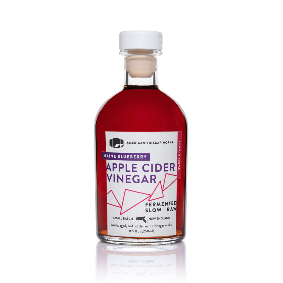 Alt Text: The front view of an 8.5 fluid ounce bottle of American Vinegar Works Blueberry Apple Cider Vinegar, showcasing a deep red liquid and a white label with purple and pink accents against a clean white background.
