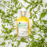 8.5oz Chardonnay Tarragon Vinegar bottle on a white tiled surface, flanked by fresh green tarragon.