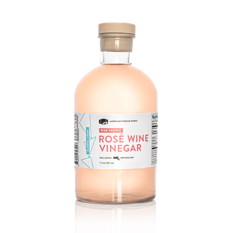 The front view of a large 1.1 Liter bottle of American Vinegar Works Pink Pacific Rosé Wine Vinegar, featuring a wide white and pink label against a clean white background.