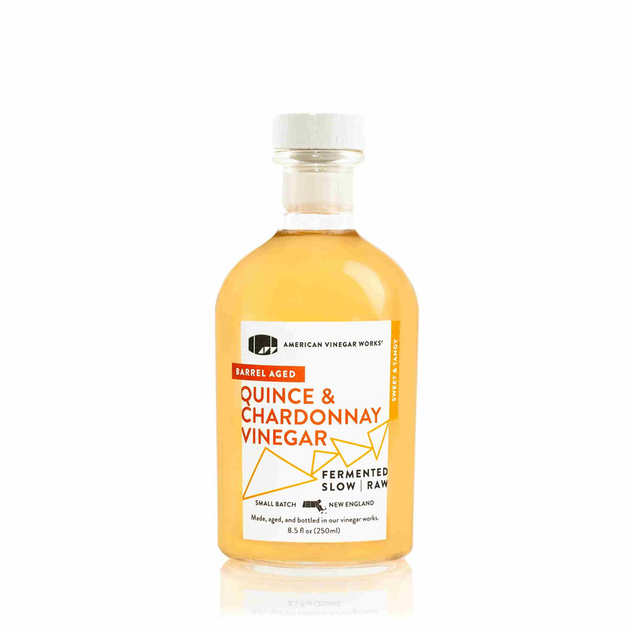 The front view of an 8.5 fluid ounce bottle of American Vinegar Works Quince and Chardonnay Vinegar, showcasing a golden yellow liquid and a white label with bright orange accents against a clean white background.