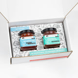A square-cropped top-down view of the open American Vinegar Works Jam Gift Set, showing two jars of jam nestled inside custom illustrated box packaging.