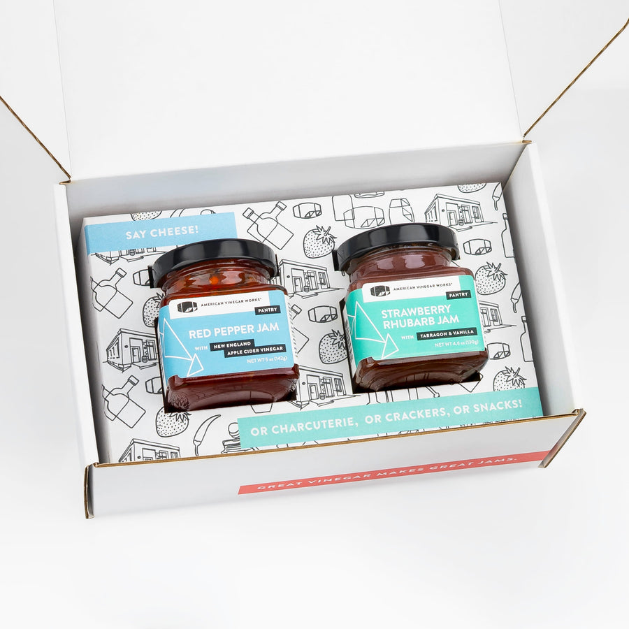 A square-cropped top-down view of the open American Vinegar Works Jam Gift Set, showing two jars of jam nestled inside custom illustrated box packaging.