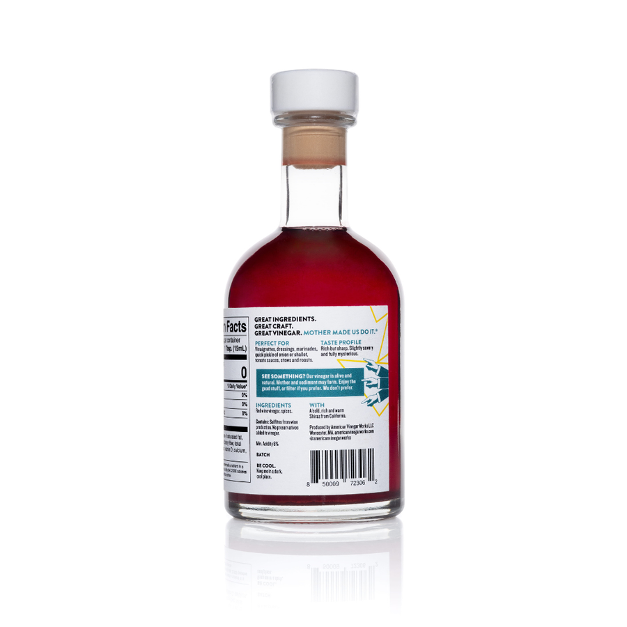 A detailed back view of an 8.5 fluid ounce bottle of American Vinegar Works Ultimate Red Wine Vinegar, showing an ingredients list with spices, a taste profile described as bold, rich, and warm, and a nutrition facts panel.