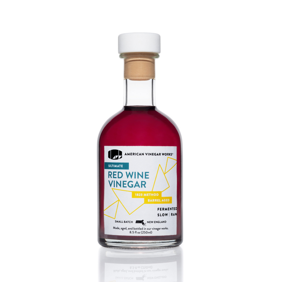 The front view of an 8.5 fluid ounce bottle of American Vinegar Works Ultimate Red Wine Vinegar, showcasing a deep red liquid and a white label with teal and yellow accents against a clean white background.