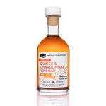 Quince and Chardonnay Vinegar clear glass bottle on white background — artisanal wine vinegar